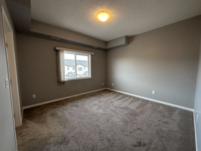 Spruce Grove apartment for rent - A room with a carpeted floor and a window with a view of buildings outside.