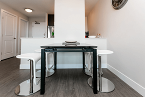 Calgary apartment for rent - A modern kitchen with a white counter and black stools.