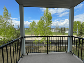 Spruce Grove apartment for rent - A balcony with a black railing and a view of a green lawn and trees.