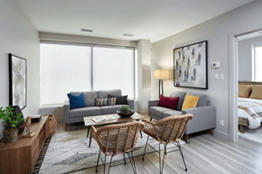 Calgary apartment for rent - A living room with a grey couch, a wooden table, and a painting on the wall.