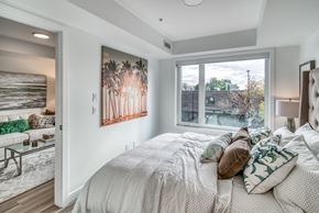 Calgary apartment for rent - A bedroom with a large bed and a painting of palm trees on the wall.