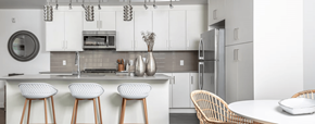 Edmonton apartment for rent - A modern kitchen with white cabinets and a white island with three stools.