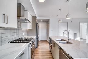Calgary apartment for rent - A modern kitchen with white cabinets and a marble countertop.