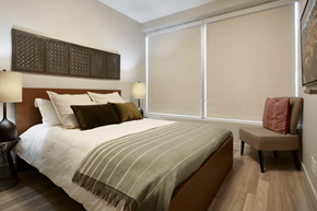 Calgary apartment for rent - A bedroom with a bed, a chair, and a lamp.