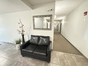 Enoch apartment for rent - A black leather couch sits in a hallway with a mirror above it.
