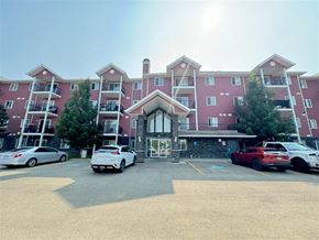 Enoch apartment for rent - A large red building with a parking lot in front of it.