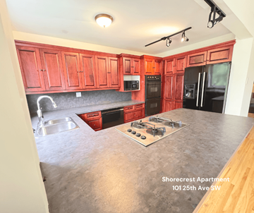 Calgary apartment for rent - A kitchen with red cabinets and a stove top oven.