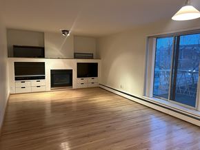 Calgary apartment for rent - A room with wooden floors and a window showing a view of a building outside.
