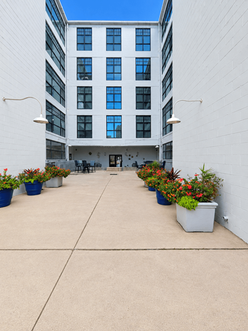 Dayton apartment for rent - A courtyard with a white building and potted plants.