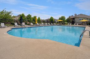 Beavercreek apartment for rent - A large swimming pool surrounded by lounge chairs and umbrellas.