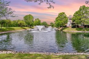 Beavercreek apartment for rent - A fountain in the middle of a pond surrounded by trees and a house in the background.
