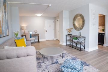 Dayton apartment for rent - A living room with a grey couch, a white coffee table, and a round mirror on the wall.