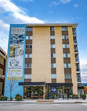 Dayton apartment for rent - A tall building with a blue and beige facade and a sign that says Flats.