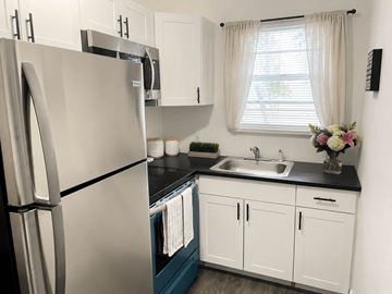 Miami apartment for rent - A kitchen with a stainless steel refrigerator and white cabinets.