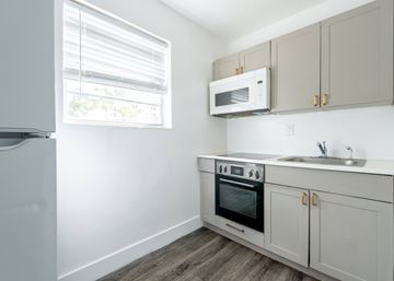 Miami apartment for rent - A kitchen with a white refrigerator, a microwave, a sink, and a stove.