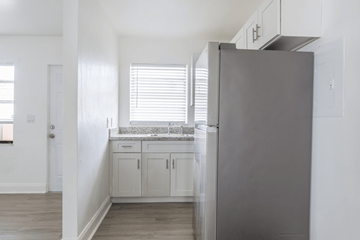 Miami apartment for rent - A kitchen with a refrigerator, cabinets, and a window with blinds.