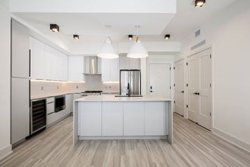 Miami apartment for rent - A modern kitchen with white cabinets and a wooden floor.
