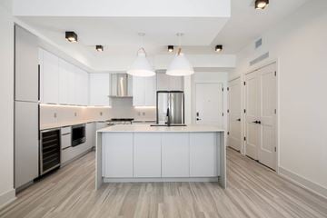 Miami apartment for rent - A modern kitchen with a white cabinetry and a wooden floor.