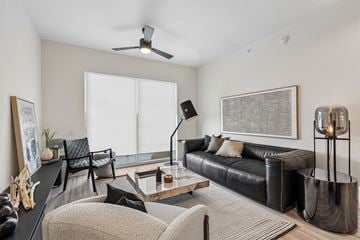 Miami apartment for rent - A living room with a black leather couch and a grey rug.