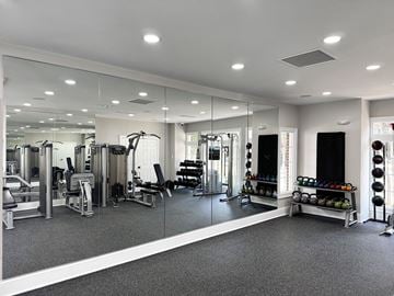 Charlotte apartment for rent - A spacious gym with a variety of equipment and a mirrored wall.
