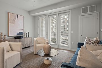 Rochester Hills apartment for rent - A living room with a large painting on the wall and a sofa with a blue cushion.