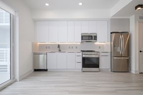 Miami apartment for rent - A modern kitchen with white cabinets and stainless steel appliances.