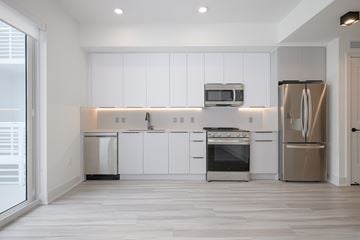 Miami apartment for rent - A modern kitchen with white cabinets and stainless steel appliances.