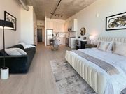 Detroit apartment for rent - A modern bedroom with a large bed and a black floor lamp.