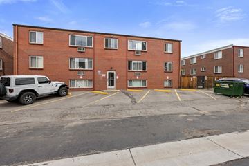 Denver apartment for rent - A parking lot in front of a red brick apartment building.