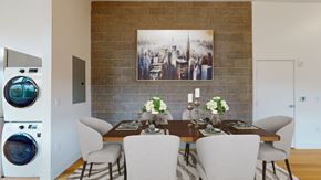 Denver apartment for rent - A dining room with a brick wall and a washing machine in the corner.