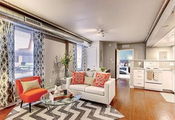 Denver apartment for rent - A living room with a white couch and a red chair.