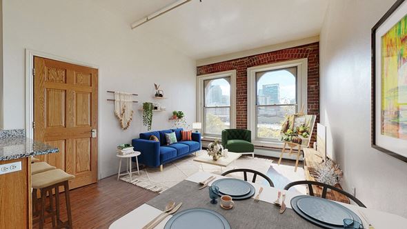 Denver apartment for rent - A living room with a blue couch and 2 large floor-to-ceiling windows showing downtown Denver views.