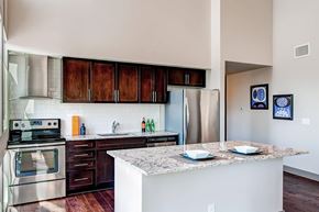Denver apartment for rent - A kitchen with a stove top oven, refrigerator, and cabinets.