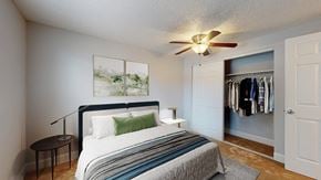 Denver apartment for rent - A bedroom with a bed, a ceiling fan, and a wardrobe.