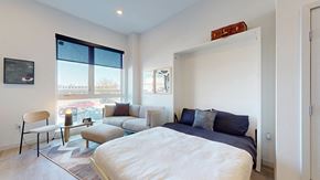 Denver apartment for rent - A bedroom with a large bed and a chair by the window.