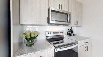 Lakewood apartment for rent - A modern kitchen with a microwave above the stove and a vase of white flowers on the counter.