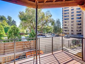 Denver apartment for rent - A balcony with a table and chairs overlooks a parking lot and buildings.