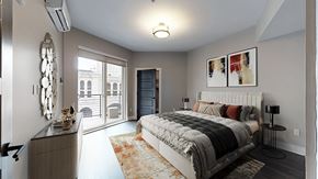 Denver apartment for rent - A bedroom with a large bed and a view of a city street through the window.