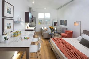 Denver apartment for rent - A modern bedroom with a large bed and a kitchen area.