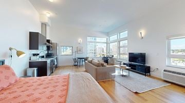 Denver apartment for rent - A modern living room with a red patterned sofa and a kitchen area with a microwave and oven.