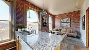 Denver apartment for rent - A kitchen with a granite countertop and a brick wall.
