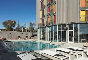 Denver apartment for rent - A swimming pool is surrounded by sun loungers in front of a modern building.