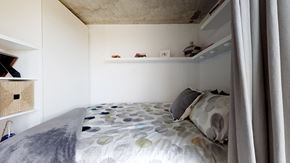 Denver apartment for rent - A bed with a grey and white patterned comforter and a grey pillow is in the foreground of the image.