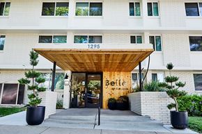 Denver apartment for rent - Building entrance with wooden canopy and landscaping at Belle on the Park Apartments, Denver, CO 80206