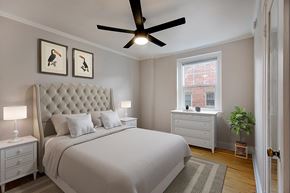 Denver apartment for rent - A bedroom with a large bed, a ceiling fan, and two framed pictures on the wall.
