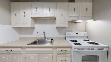 Denver apartment for rent - A white stove and sink in a kitchen with white cabinets.
