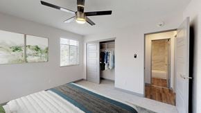 Denver apartment for rent - A bedroom with a ceiling fan and a bed with a striped rug on the floor.