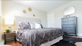 Arvada apartment for rent - A bedroom with a large bed and a lamp on a side table.