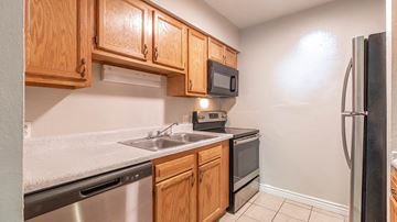 Arvada apartment for rent - A kitchen with wooden cabinets and a black fridge.