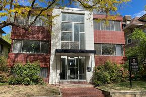 Denver apartment for rent - A building with a red and white facade has a black sign in front of it.